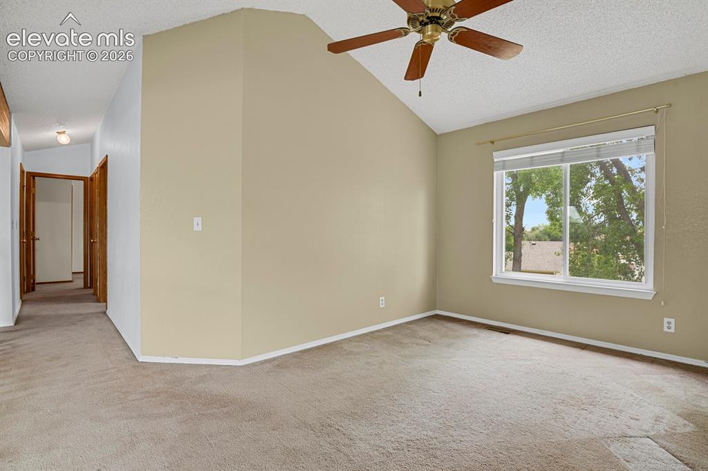 Image 46 of 48: Room featuring vaulted ceiling, ceiling fan with light fixture, neutral-ton