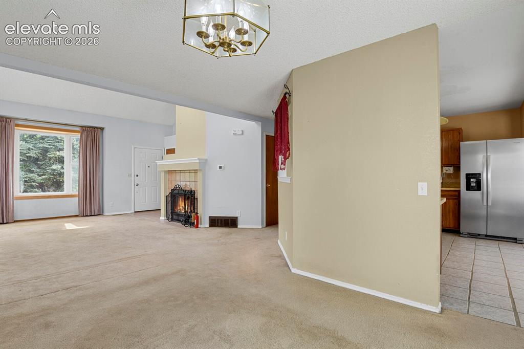 Image 7 of 48: Open-concept living area with a built-in fireplace, neutral carpeting, and 