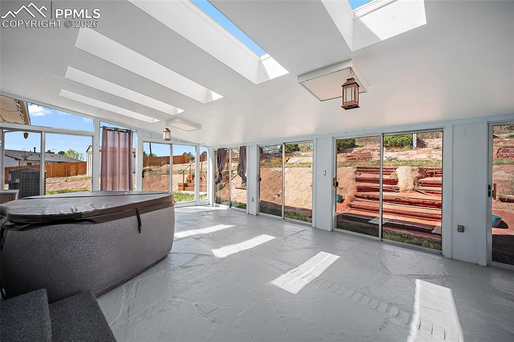 Image 35 of 50: Enclosed sunroom with hot tub.