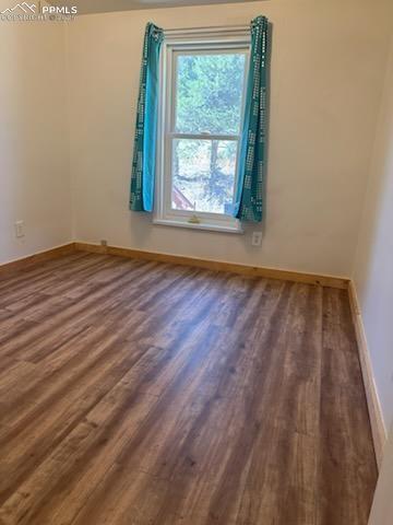Image 16 of 23: Spare room featuring dark wood finished floors and baseboards