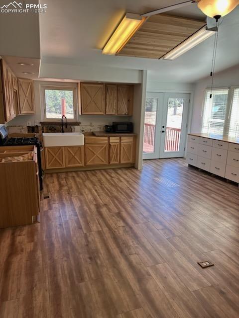 Image 19 of 23: Kitchen with french doors, stainless steel gas range, plenty of natural lig
