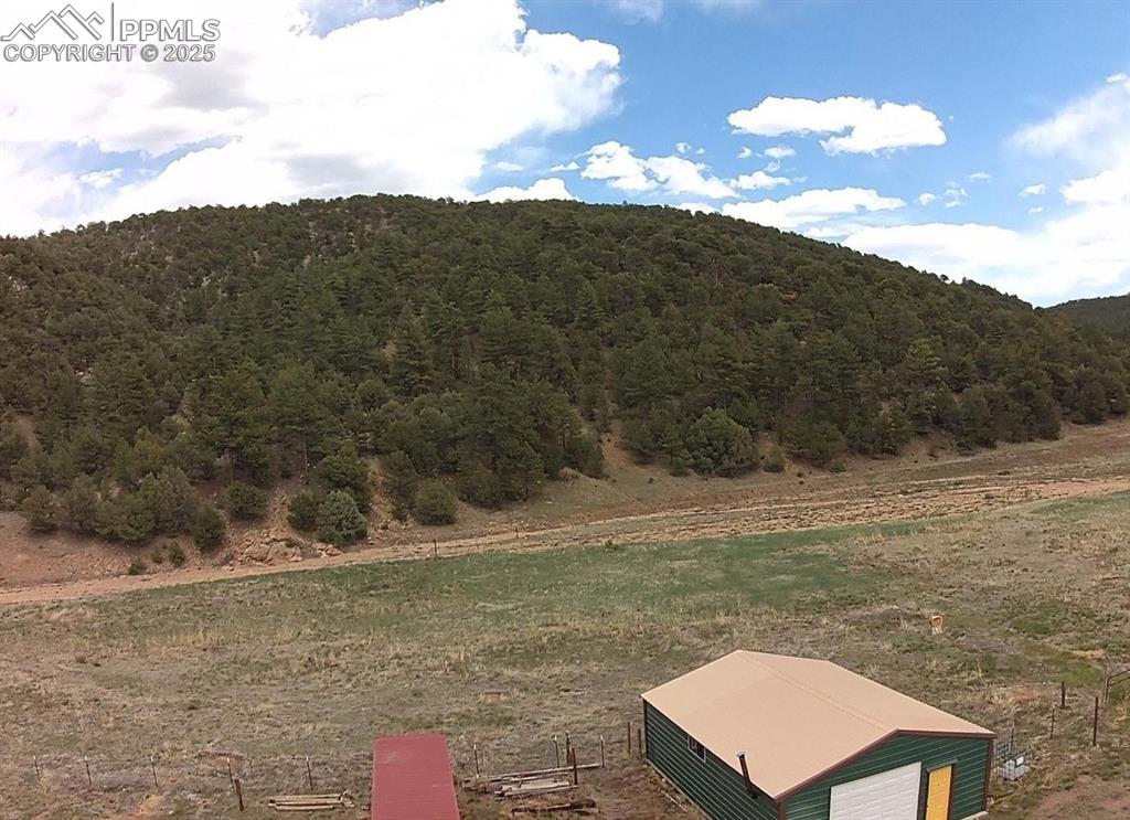 Image 6 of 23: View of yard with a wooded view, an outbuilding, a detached garage, and a v