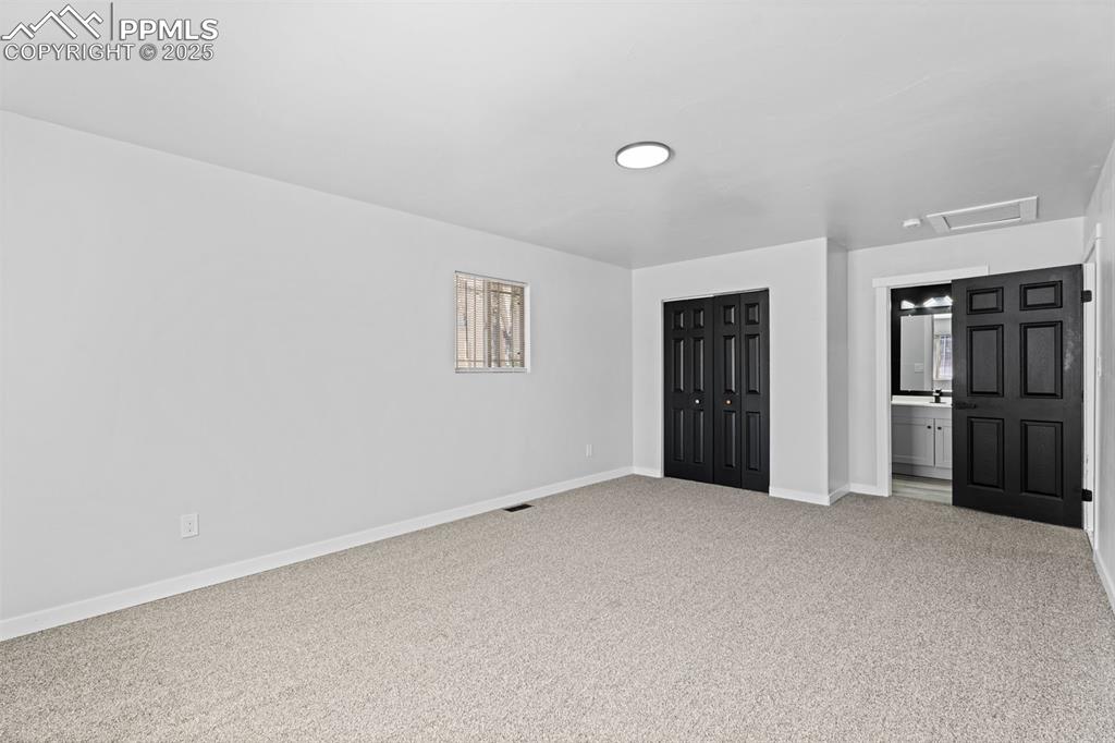 Image 20 of 32: Unfurnished bedroom featuring attic access, carpet floors, a closet, and en