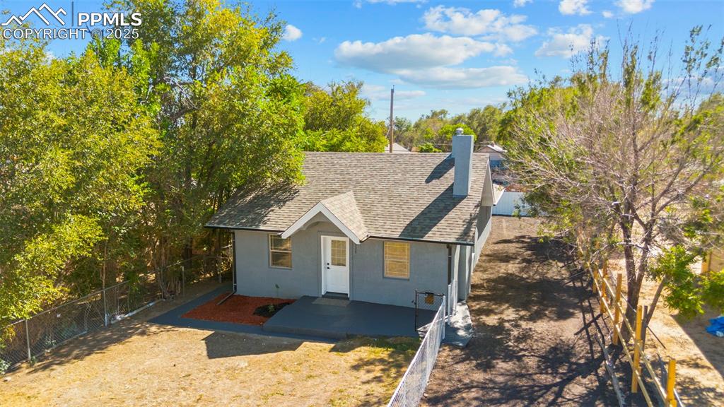 Image 24 of 32: View of front of property with a shingled roof, a chimney, and stucco sidin