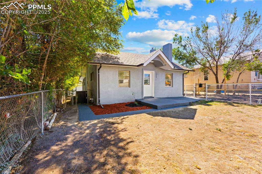Image 3 of 32: View of front facade featuring a chimney, stucco siding, and roof with shin