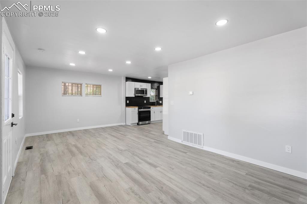 Image 6 of 32: Unfurnished living room with recessed lighting and light wood finished floo