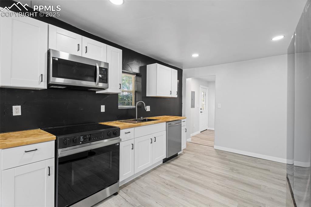 Image 8 of 32: Kitchen featuring stainless steel appliances, tasteful backsplash, wood cou