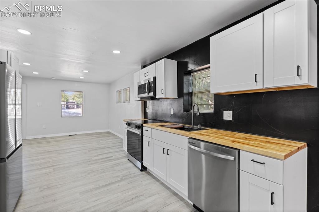Image 9 of 32: Kitchen with wood counters, appliances with stainless steel finishes, taste