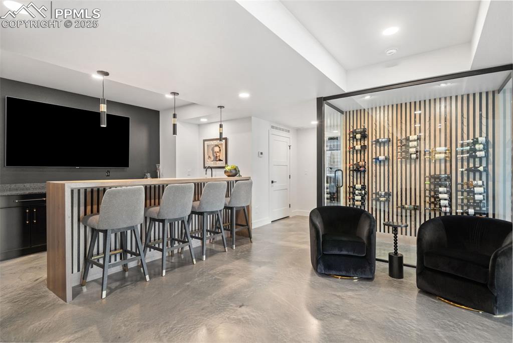 Image 36 of 50: Adjacent to the glass encased wine cellar is the walk behind bar with tons