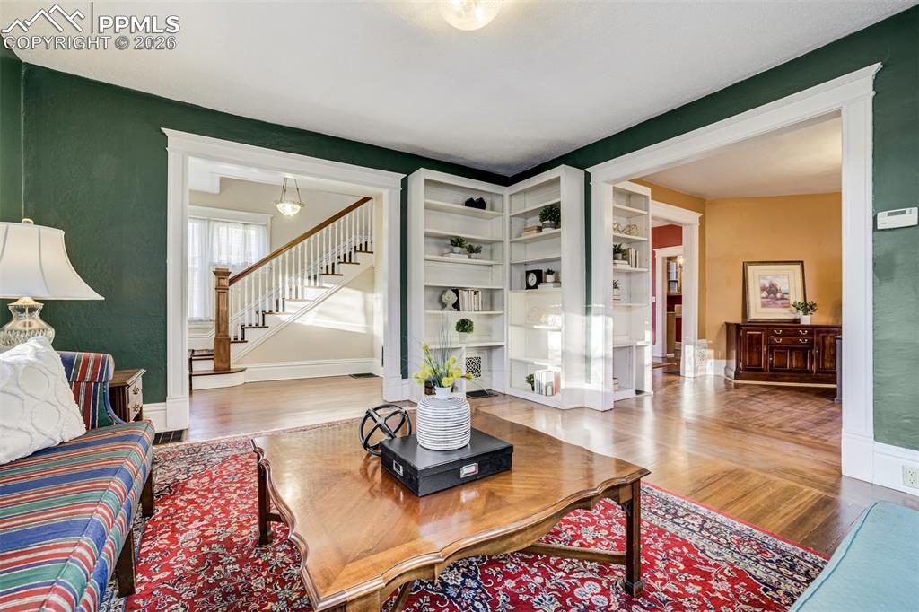 Image 7 of 50: Living room provides built in shelving and opens to family room and entry
