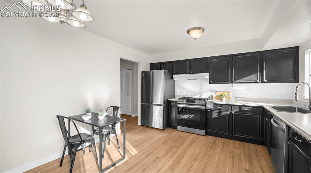 Image 10 of 32: Kitchen with dark cabinetry, light countertops, stainless steel appliances,