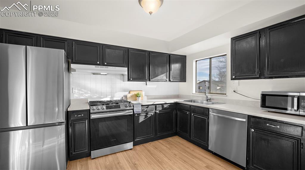Image 11 of 32: Kitchen featuring dark cabinetry, stainless steel appliances, light counter