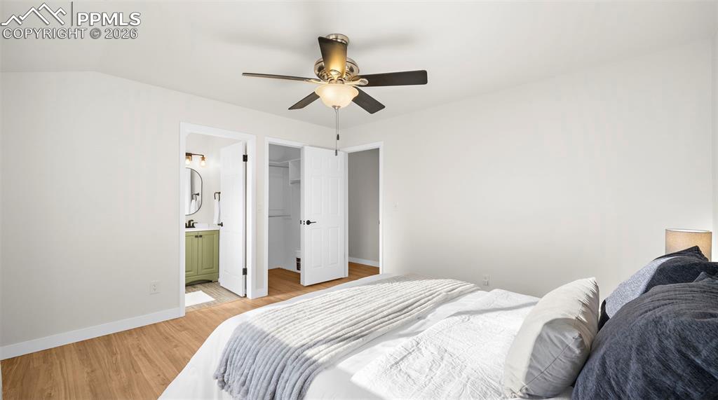 Image 15 of 32: Bedroom with a walk in closet, light wood-style floors, and a ceiling fan