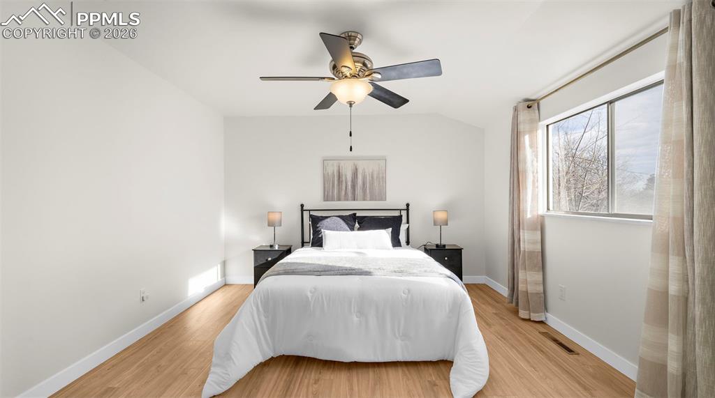 Image 16 of 32: Bedroom with light wood-style flooring, ceiling fan, and vaulted ceiling