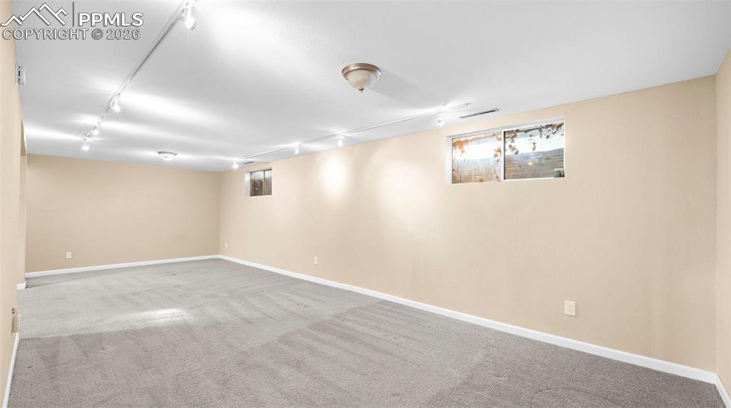 Image 23 of 32: Below grade area featuring rail lighting and light colored carpet