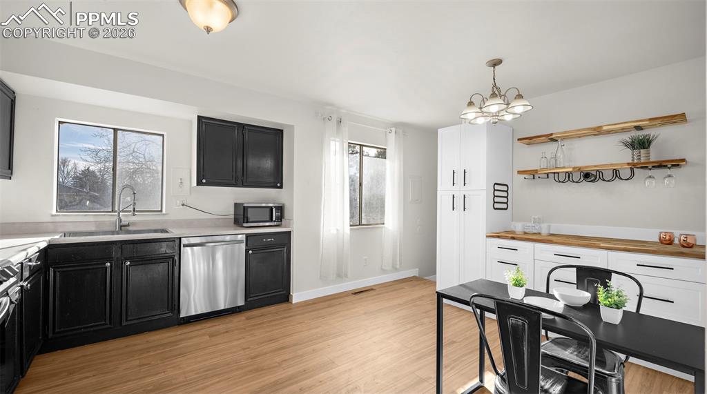 Image 9 of 32: Kitchen with dark cabinets, stainless steel appliances, suspended lighting,