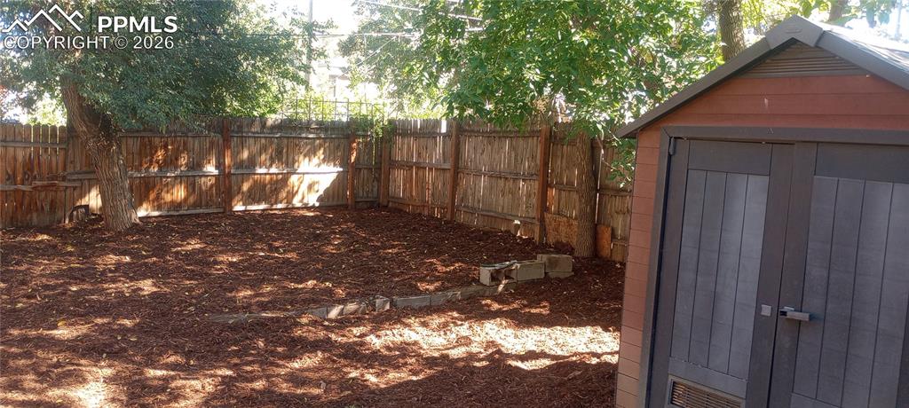 Image 10 of 10: Fenced backyard with storage shed.