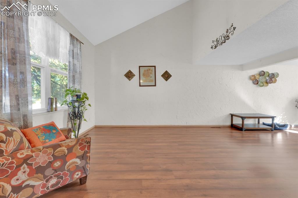 Image 10 of 32: Sitting room featuring lofted ceiling, wood finished floors, and a textured