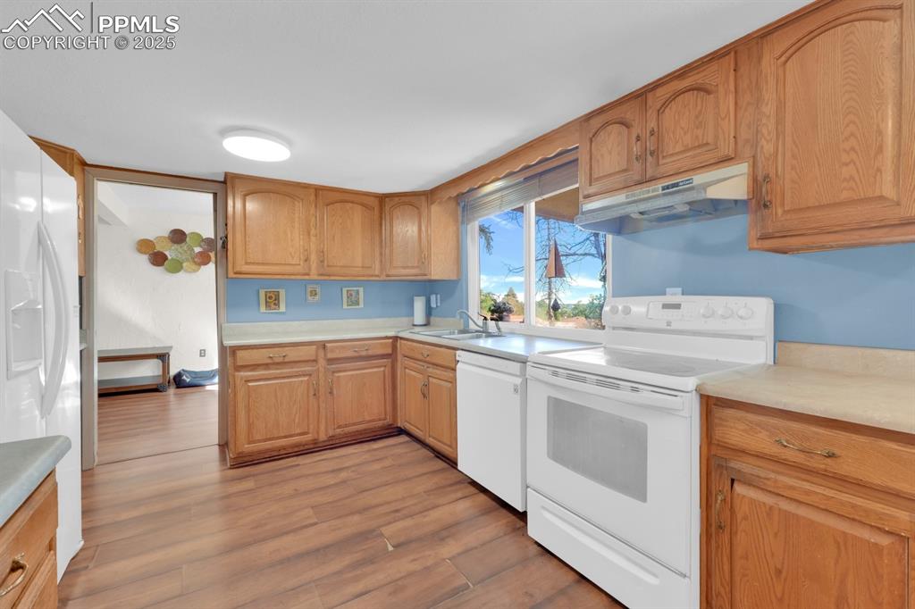 Image 15 of 32: Kitchen with white appliances, light countertops, under cabinet range hood,