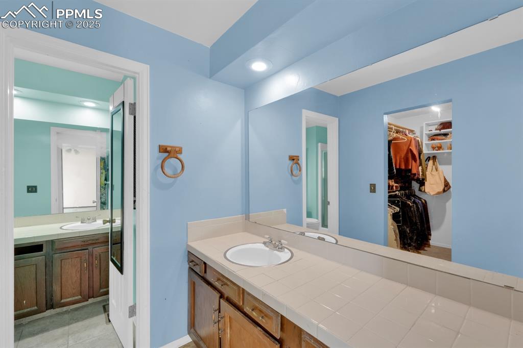 Image 20 of 32: Primary full bathroom featuring vanity, a walk in closet, and recessed ligh