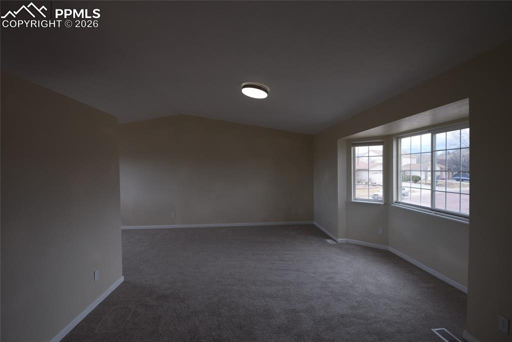 Image 10 of 42: The living area features vaulted ceilings, carpeted flooring, and a bay win