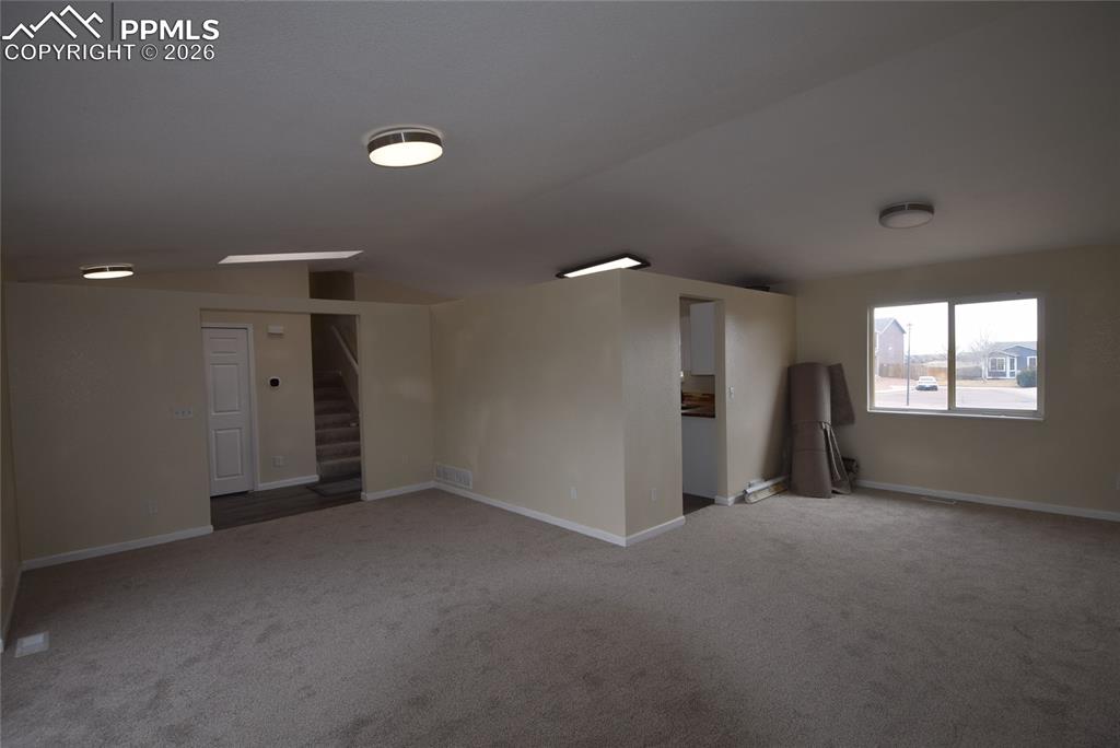 Image 11 of 42: Spacious room with light-colored carpeting, neutral painted walls, and over