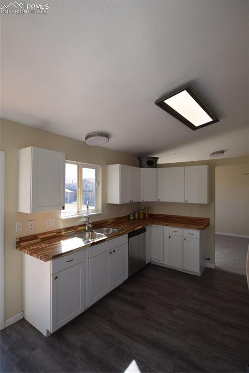 Image 12 of 42: The kitchen features white cabinetry, wood-look countertops, a stainless st