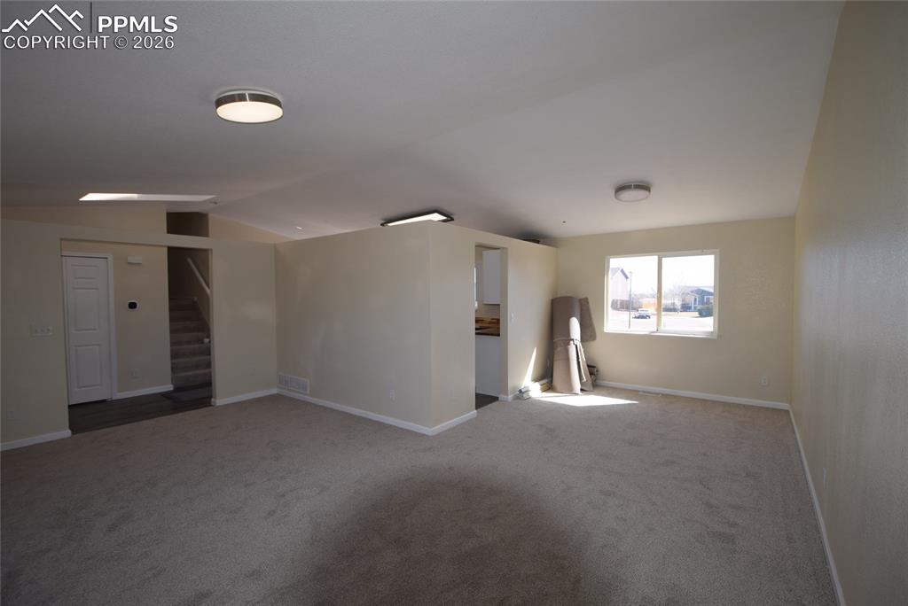 Image 18 of 42: Spacious living area featuring neutral-toned walls, plush carpet flooring, 