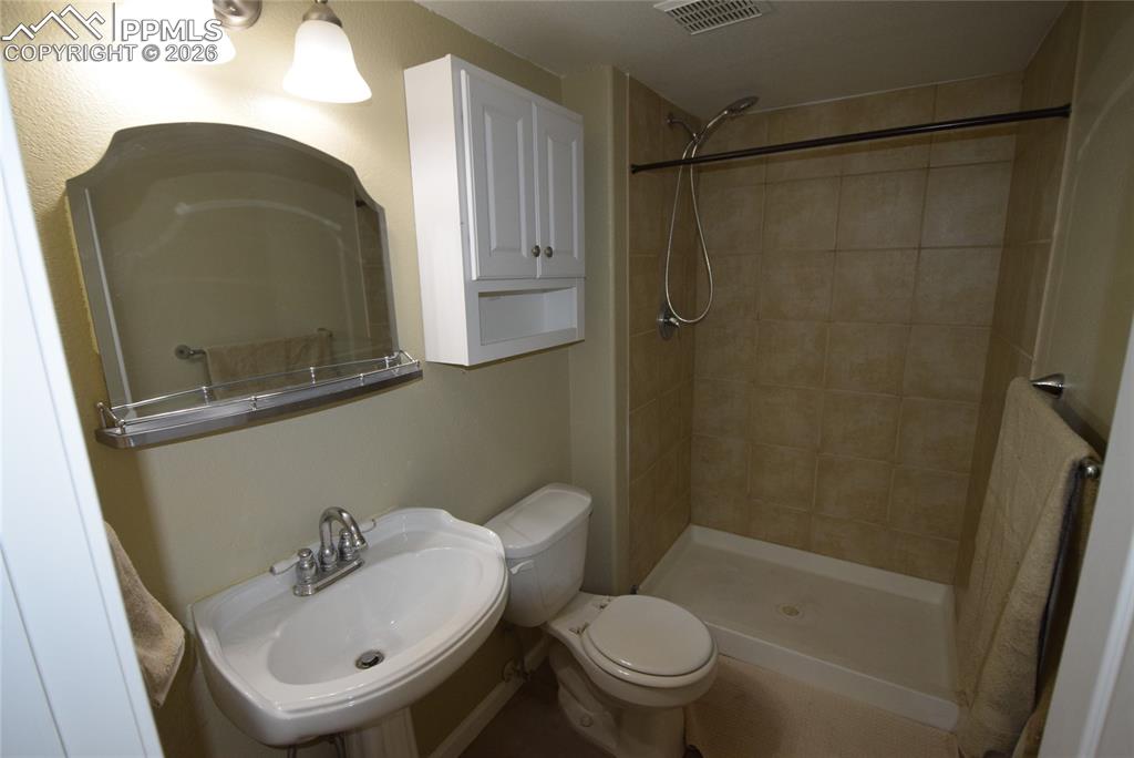 Image 24 of 42: This bathroom features a pedestal sink with a mirrored vanity and overhead 
