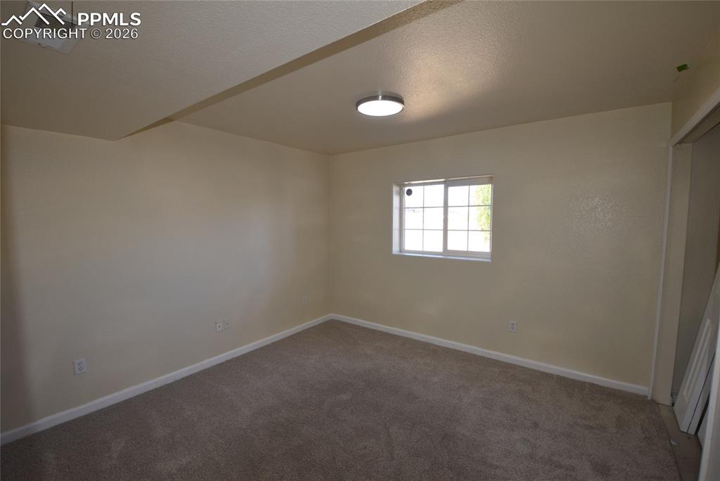Image 27 of 42: The room features neutral-toned carpeting, light-colored walls, and a windo