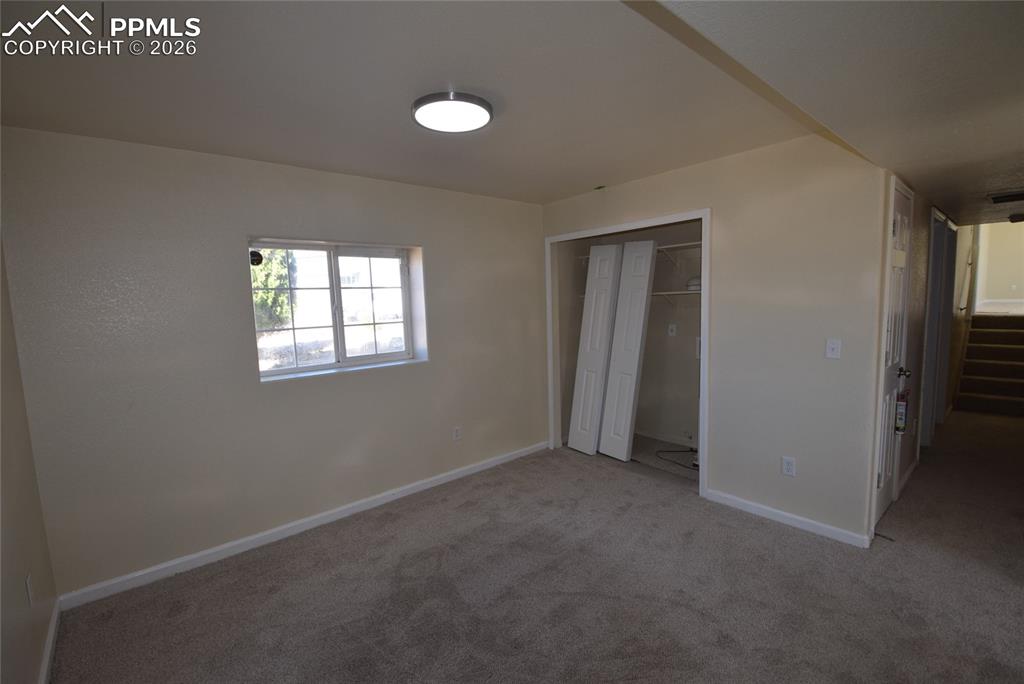 Image 28 of 42: This room features neutral-toned walls, carpeted flooring, and a window wit