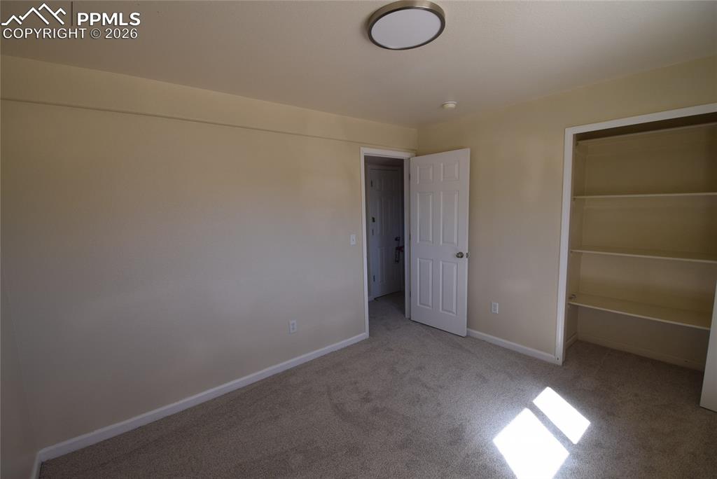 Image 32 of 42: The room features neutral-toned walls, carpeted flooring, and a built-in sh