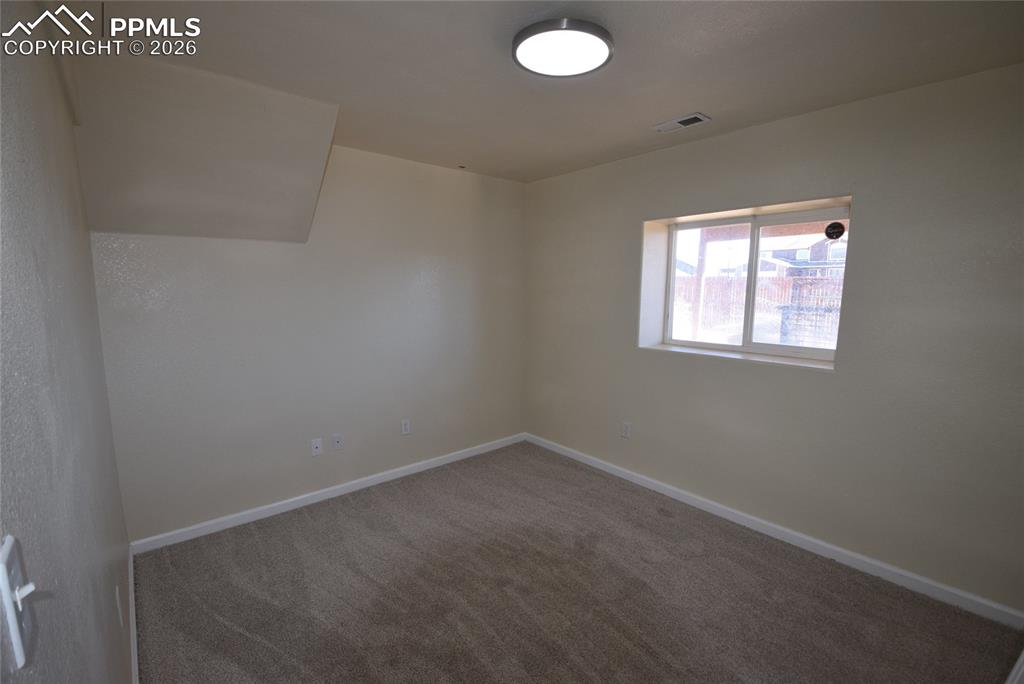 Image 33 of 42: This room features neutral-toned carpet, light-colored walls, and a window 