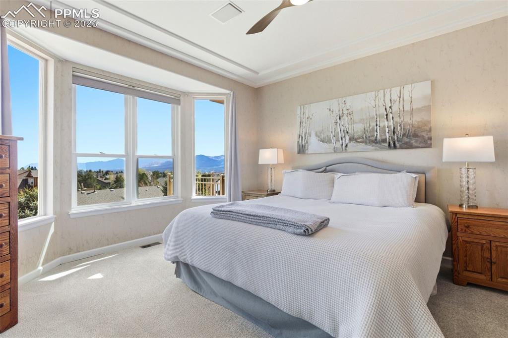Image 13 of 40: Bedroom featuring a prominent bay window with a mountain backdrop, neutral-