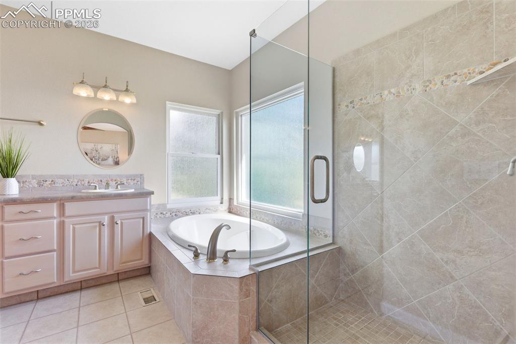Image 15 of 40: Bathroom featuring a built-in soaking tub with corner windows, a glass-encl
