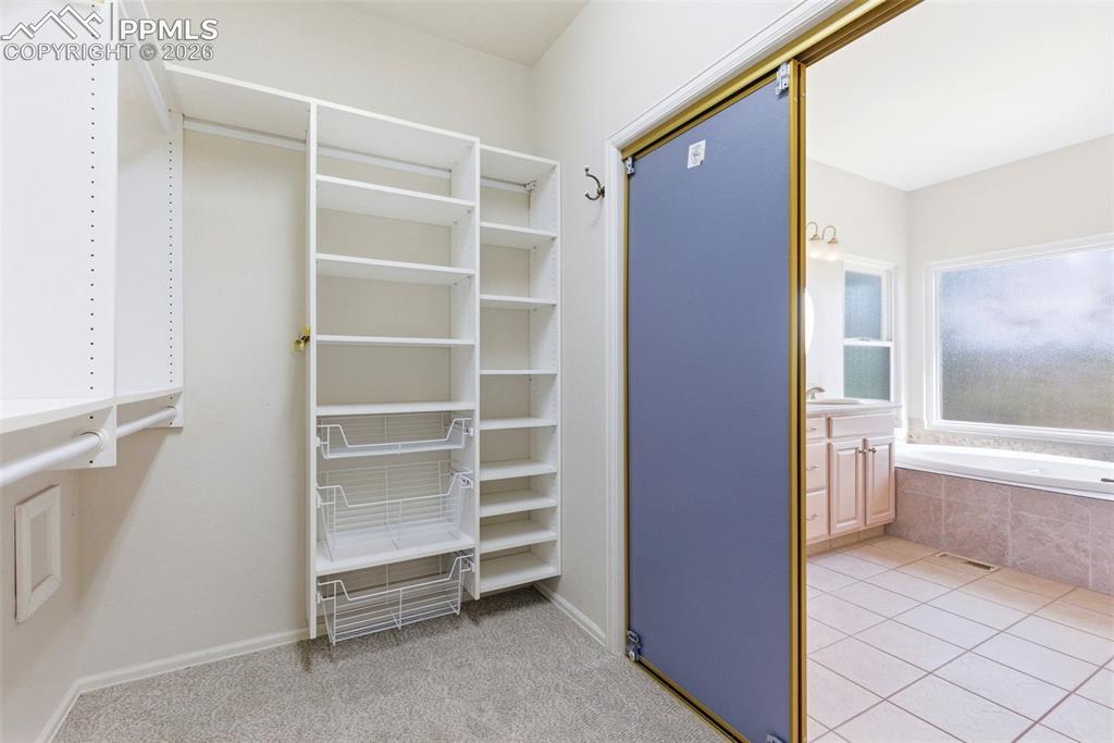 Image 17 of 40: Custom closet system featuring multiple shelves, hanging rods, and pull-out