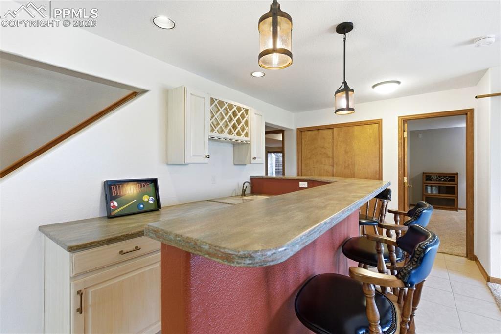 Image 21 of 40: Built-in wet bar featuring a textured countertop, integrated sink, overhead