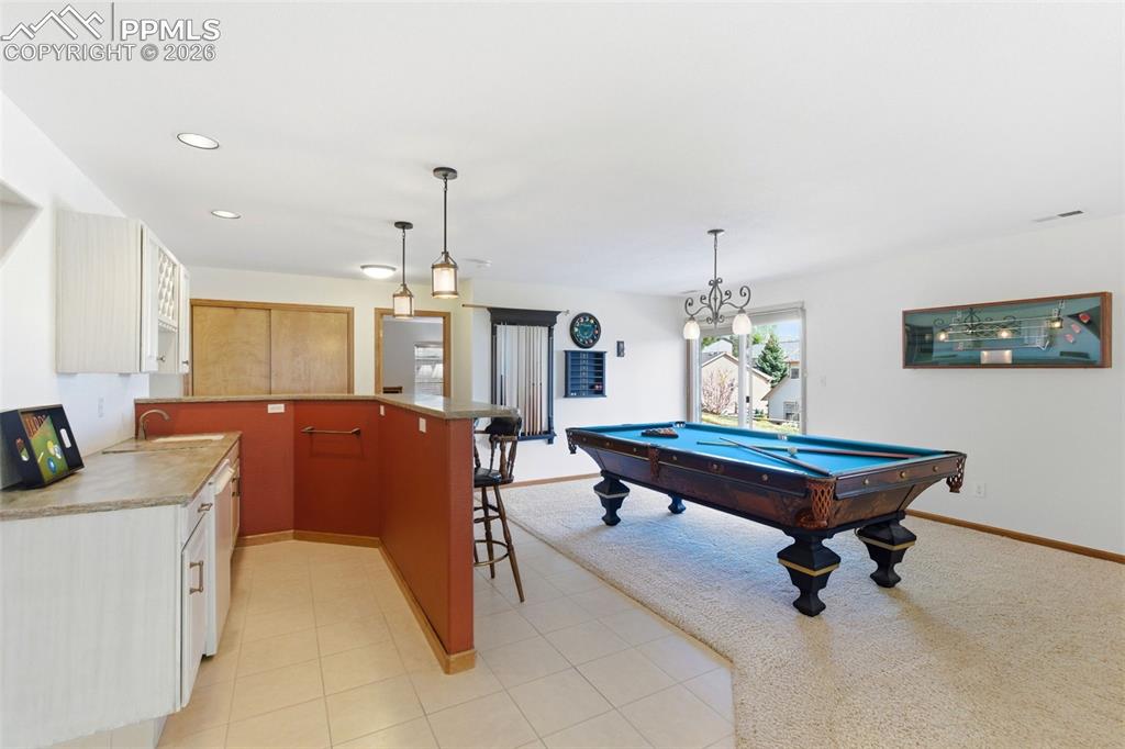 Image 22 of 40: Finished room featuring a built-in wet bar with white cabinetry, a countert