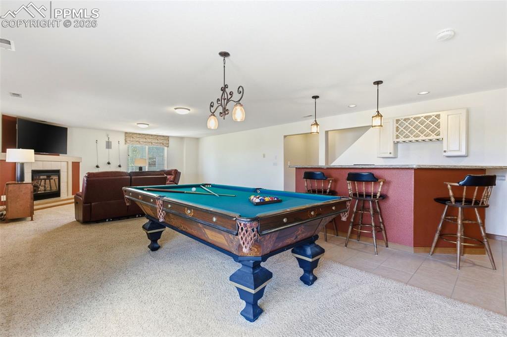 Image 23 of 40: Recreation room featuring a built-in wet bar with pendant lighting, a tile-