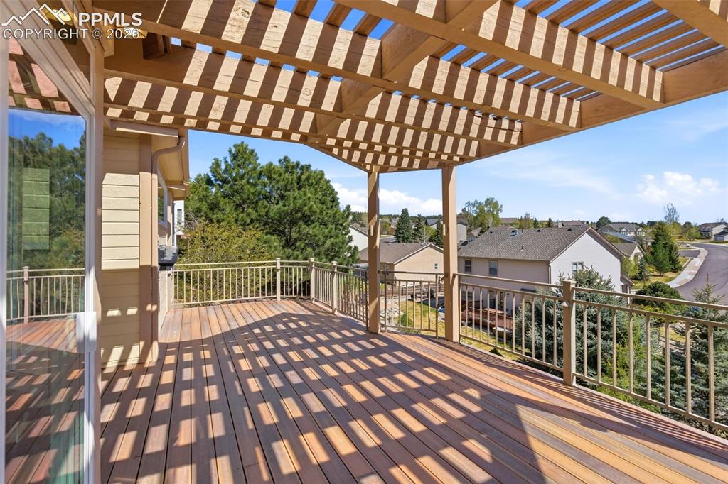 Image 32 of 40: Expansive outdoor deck featuring wood-finish flooring, a full pergola, and