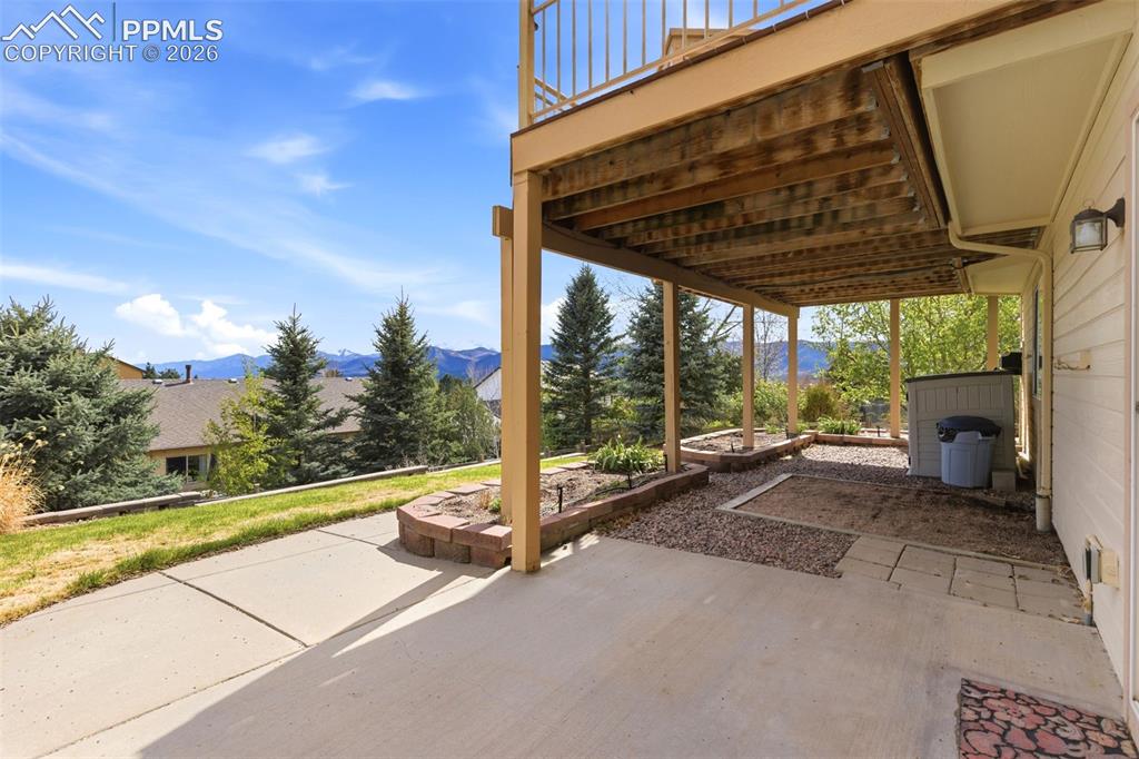Image 33 of 40: Covered patio area with concrete flooring, supported by a wooden deck struc