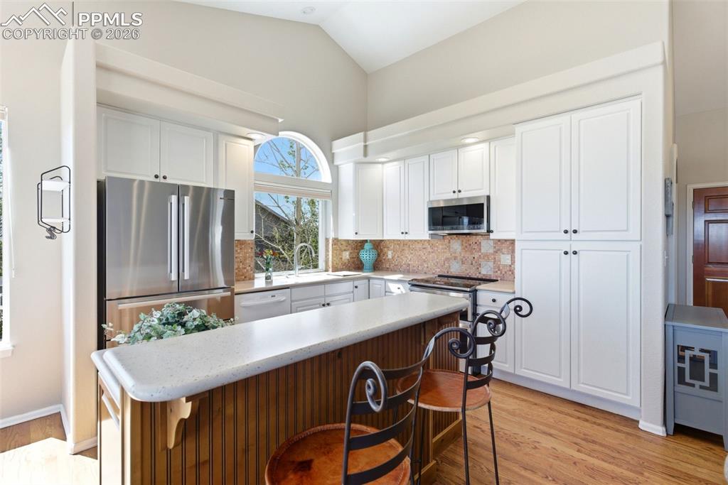 Image 6 of 40: Kitchen featuring white cabinetry, stainless steel appliances, a breakfast