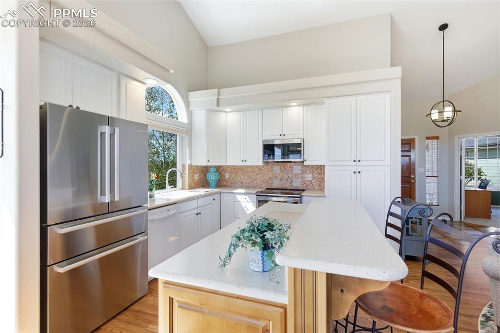 Image 7 of 40: Open-concept kitchen featuring a vaulted ceiling and an arched window