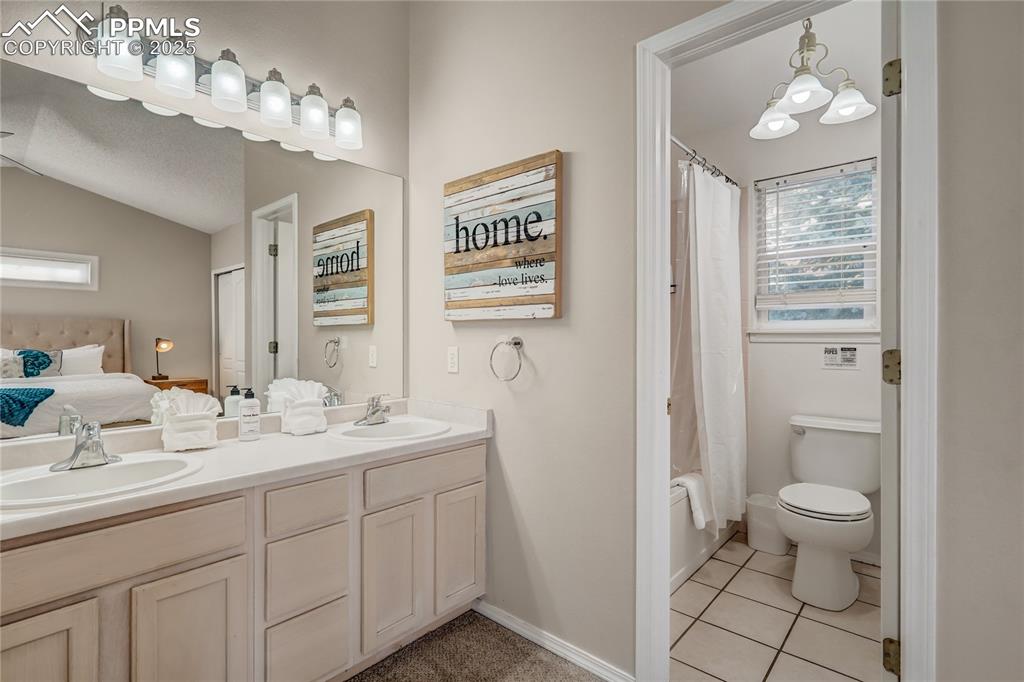Image 15 of 35: Primary bathroom featuring a solid counter top, two sinks,  light tile patt
