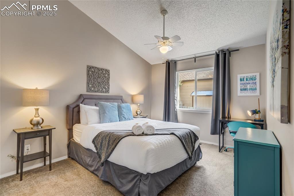Image 17 of 35: 2nd bedroom with vaulted ceiling, light colored carpet and a ceiling fan. 