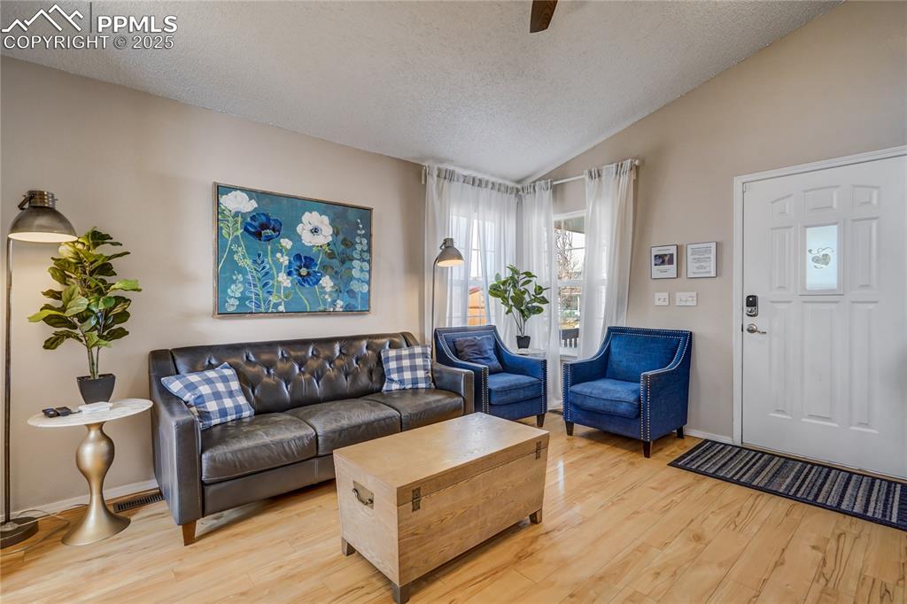 Image 2 of 35: Living area featuring a vaulted ceiling, light wood finished and ceiling fa