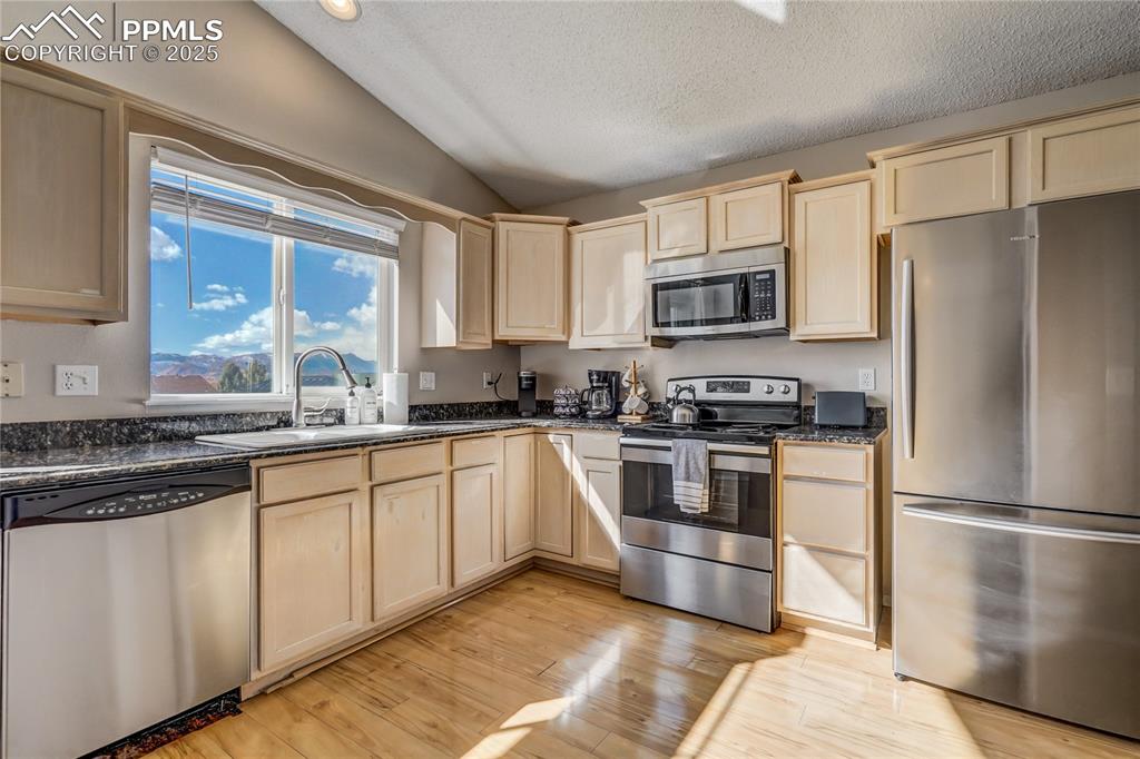 Image 7 of 35: Kitchen with views of Pikes Peak, stainless steel appliances, light wood fl