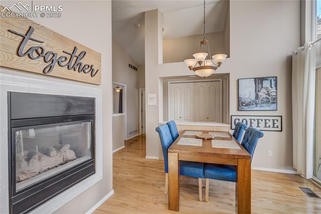 Image 9 of 35: Dining space featuring high vaulted ceiling, light wood flooring, a chandel