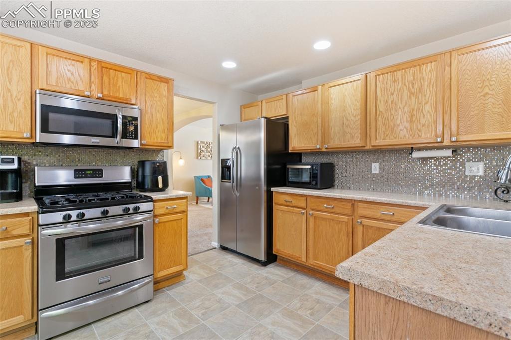 Image 10 of 46: Kitchen featuring appliances with stainless steel finishes, arched walkways