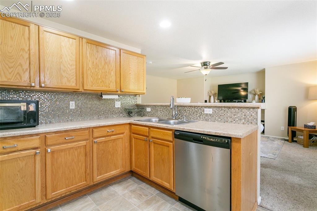 Image 11 of 46: Kitchen with stainless steel dishwasher, ceiling fan, a peninsula, backspla